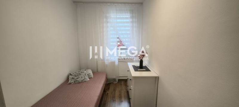 Einfaches Interieur einer 3-Zimmer-Wohnung mit Bett und Boden in Holzoptik.