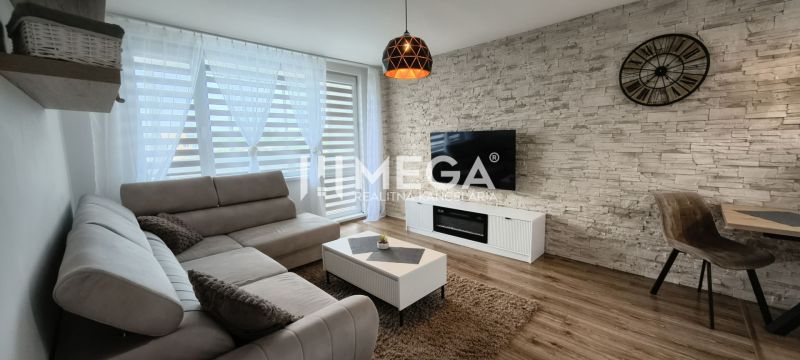 Wohnzimmer in einer 3-Zimmer-Wohnung mit Holzboden und einem Fernseher an der Steinwand.