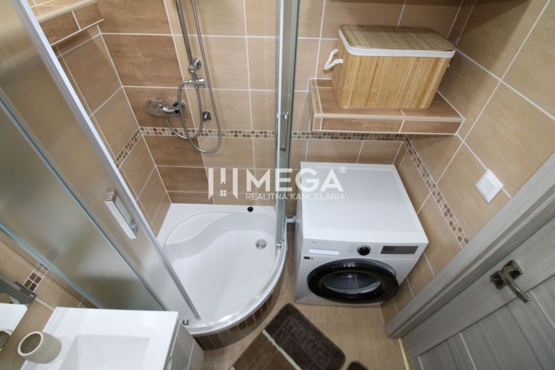 Badezimmer mit Dusche und Waschmaschine in einer 3-Zimmer-Wohnung, mit braunen Fliesen.