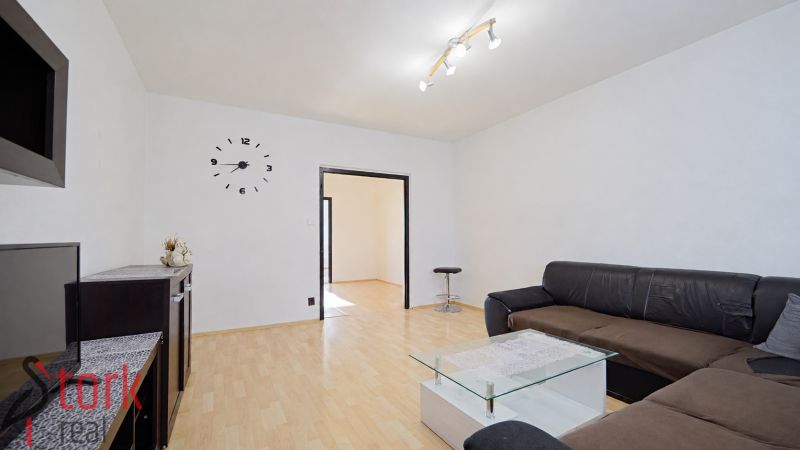 Wohnzimmer in einer 3-Zimmer-Wohnung mit Sofa, Glastisch und Holzboden.