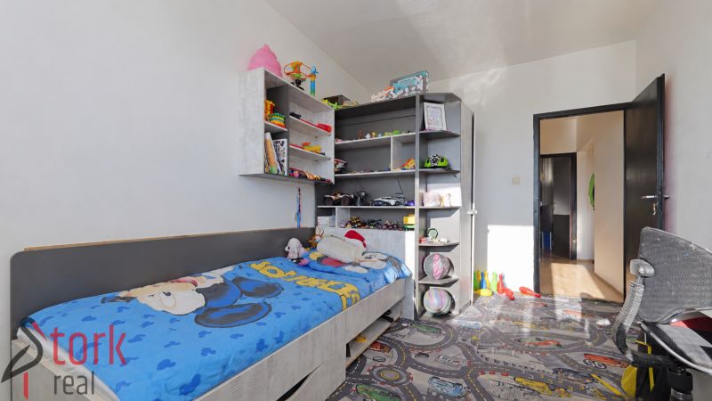Kinderzimmer in einer 3-Zimmer-Wohnung mit einem Bett und Regalen voller Spielzeug und Bücher.