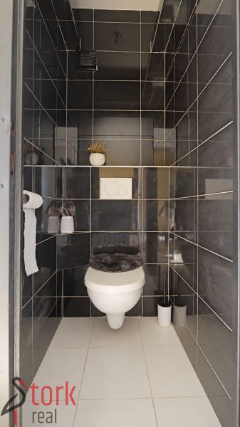 Badezimmer in einer 3-Zimmer-Wohnung mit dunkelgrauen Fliesen und weißer Sanitärausstattung.