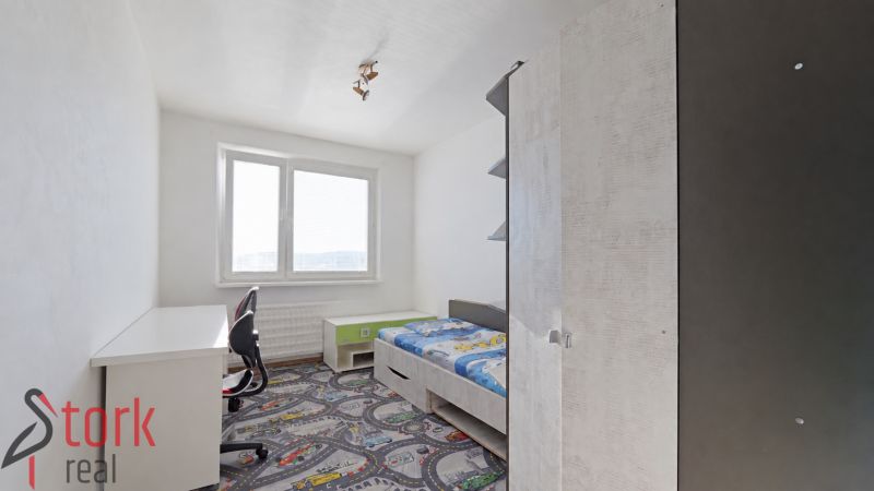 Kinderzimmer in einer 3-Zimmer-Wohnung mit Bett und Schreibtisch auf einem bunten Teppich.