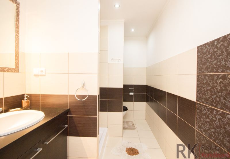 Badezimmer in einer 2-Zimmer-Wohnung mit braunen und beigen Fliesen, Waschbecken und Spiegel.