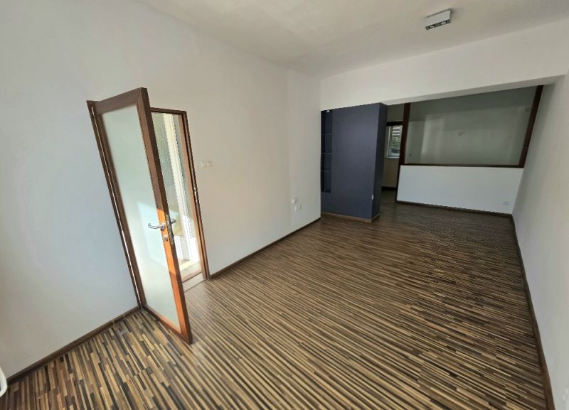 Ein Zimmer einer 2-Zimmer-Wohnung mit Holzboden und Glastüren.