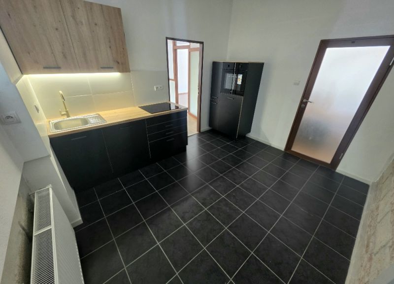 Küche in einer 2-Zimmer-Wohnung mit schwarzen Schränken und strukturiertem Boden.