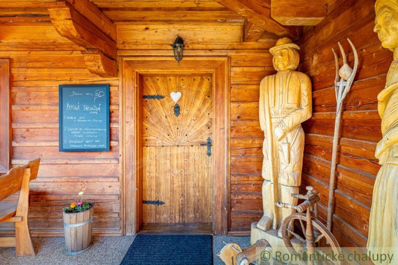 Ein Holzhaus in Machulince, mit Skulpturen und einer Wandtafel am Eingang.