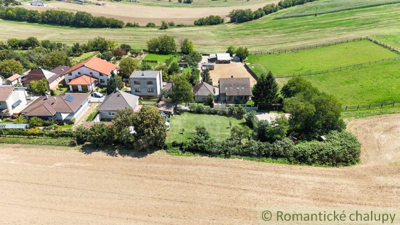 Dorfgärten in Pastuchov mit Häusern, umgeben von Feldern und Wiesen.