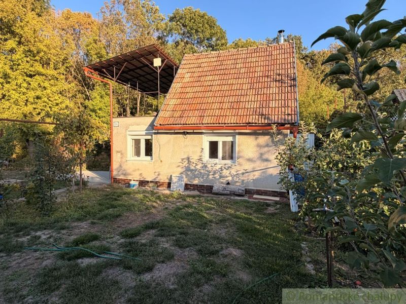 Ein Ferienhaus in Nové Zámky, umgeben von Grün, mit einem roten Dach in einer natürlichen Umgebung.