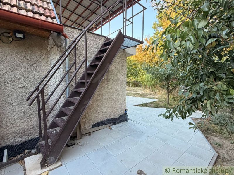 Das Äußere der Hütte in Nové Zámky mit einer Metalltreppe und einer von Grün umgebenen Terrasse.