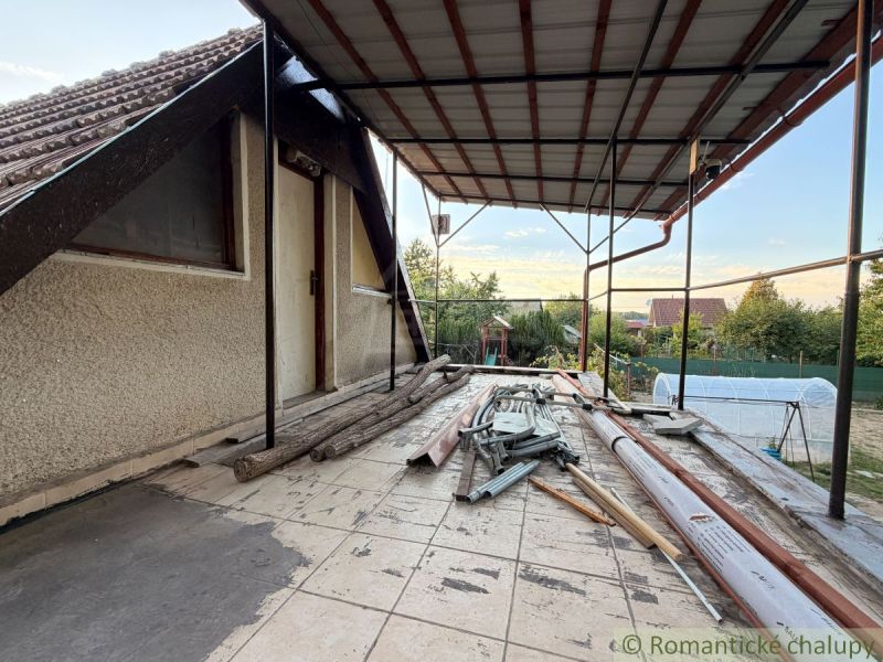 Die Terrasse der Hütte in Nové Zámky mit Unordnung und Baumaterial, ein ruhiger Garten im Hintergrund.