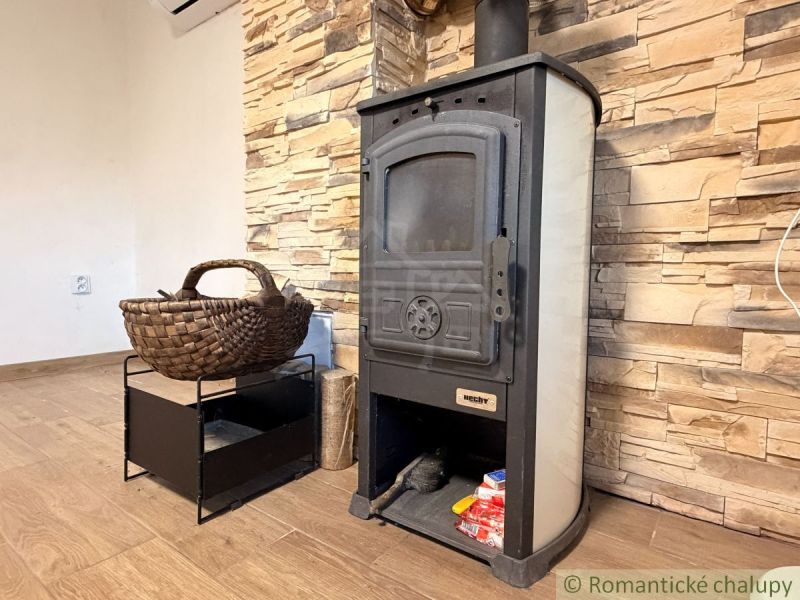 Kaminofen mit geflochtenem Korb und Steinwand, Boden mit Holzdekor in der Hütte.