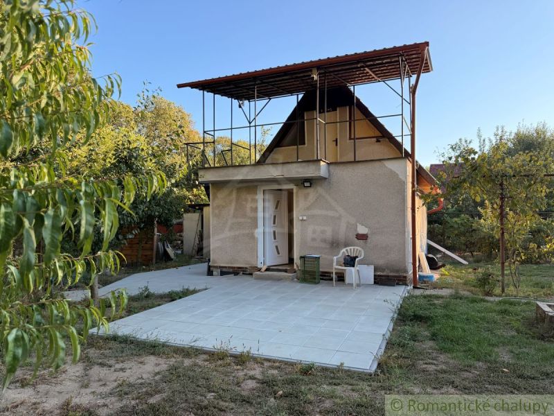 Eine Hütte in Nové Zámky, umgeben von Grün, mit einer Außenterrasse auf einer befestigten Fläche.