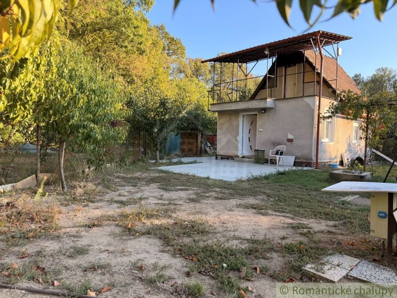 Eine Hütte in Nové Zámky mit Garten und Terrasse, umgeben von Bäumen.