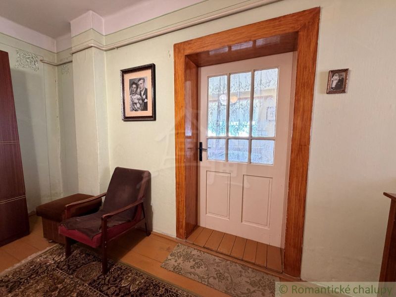 Ein Zimmer in einem Einfamilienhaus mit einem Sessel, einem Teppich und Glastüren.