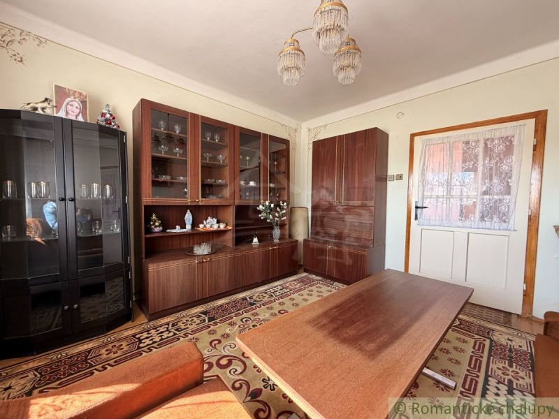 Wohnzimmer in einem Einfamilienhaus mit Schränken, einem Tisch und einem gemusterten Teppich.