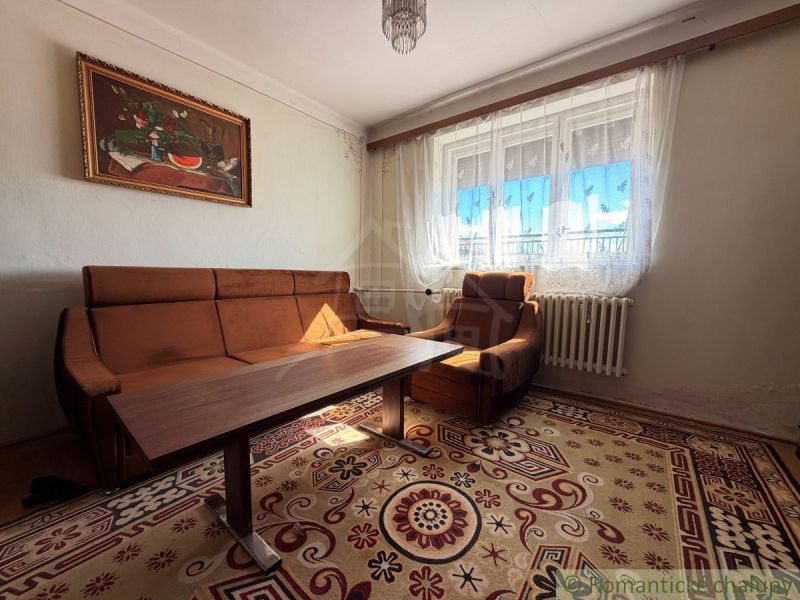 Wohnzimmer in einem Einfamilienhaus mit braunem Sofa und Vorhängen.