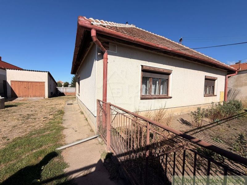 Ein Einfamilienhaus in Hurbanovo mit einem großen eingezäunten Garten, einer angrenzenden Garage und einem Rasenstück.