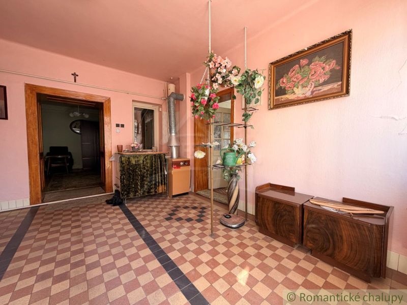 Innenraum eines Einfamilienhauses mit rosa Wänden, Blumendekoration und Schachbrettboden.