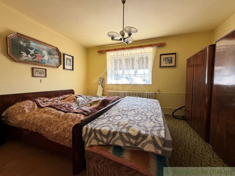 Schlafzimmer im Einfamilienhaus mit Bett und Wohnwand, an der Wand Bilder.