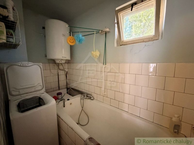 Kúpeľňa v rodinnom dome s vaňou, bojlerom a práčkou.
