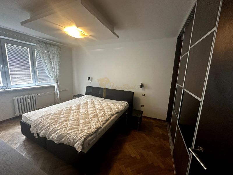 Schlafzimmer in einer 2-Zimmer-Wohnung mit Bett, Kleiderschrank und Boden in Holzoptik.