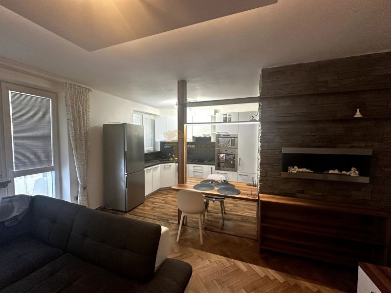 Wohnzimmer mit Küchenzeile, Sofa und Holzboden in einer Zweizimmerwohnung.