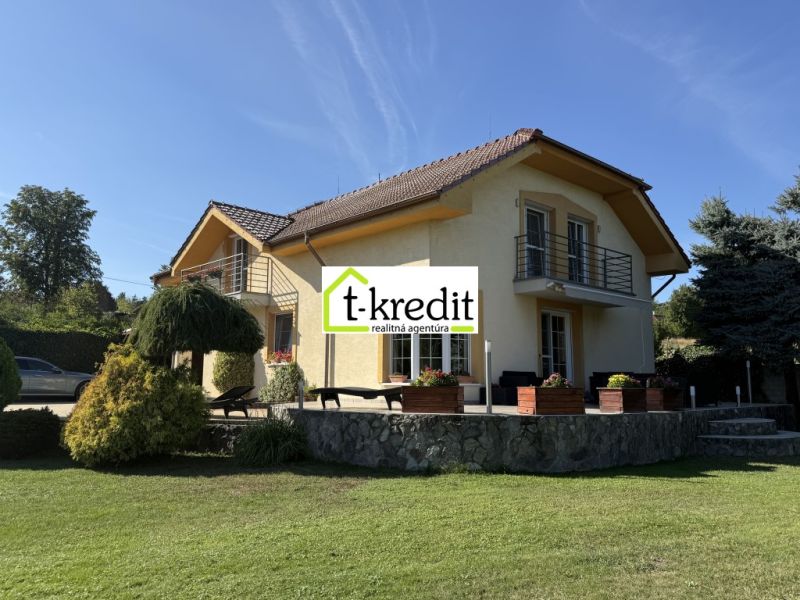 Ein Einfamilienhaus in Zlaté Moravce, umgeben von Grün, mit einer Steinterrasse und einem Balkon.