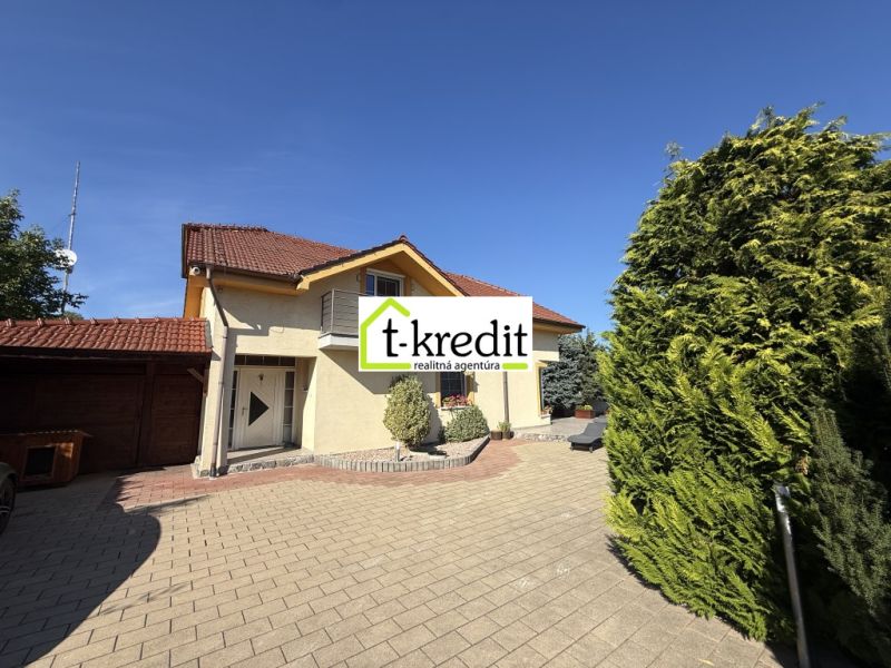 Ein Einfamilienhaus in Zlaté Moravce mit Zufahrtsstraße, Balkon und grünen Bäumen.