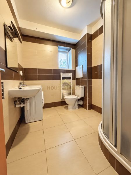 Badezimmer in einem Studio-Apartment mit Dusche, Waschmaschine, Waschbecken und Toilette.