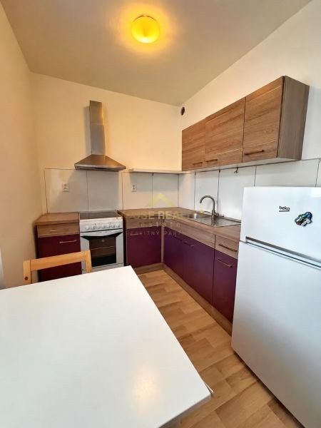 Küche in einem Studio-Apartment mit Eckküche, Tisch und Boden in Holzoptik.