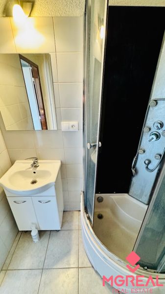 Badezimmer mit Waschbecken und Duschkabine in einer Einzimmerwohnung.
