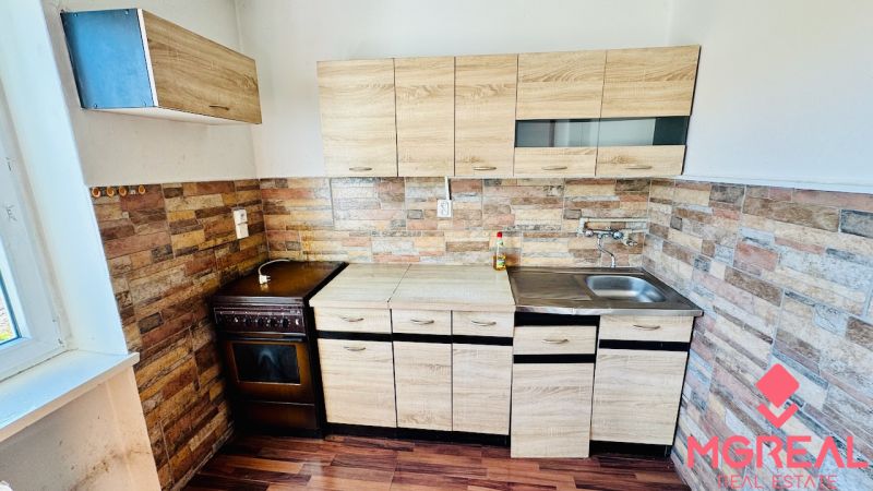 Küche in einer Einzimmerwohnung mit Holzelementen und Steinwandverkleidung.