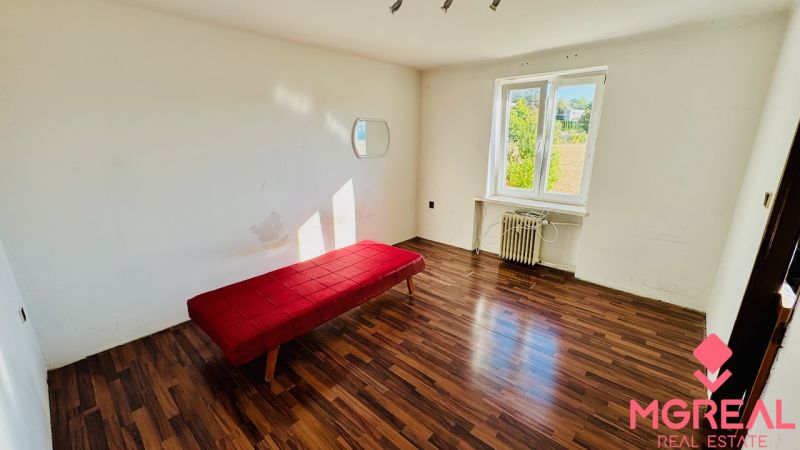 Einfaches Interieur einer Einzimmerwohnung mit Holzboden und rotem Sofa.