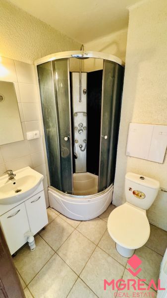 Badezimmer mit Dusche, Waschbecken und Toilette in einer Einzimmerwohnung.
