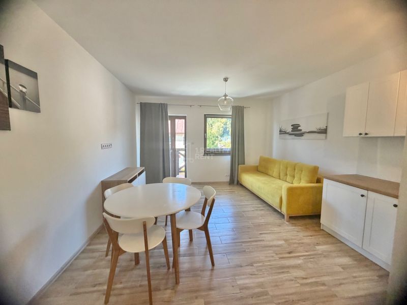 1-Zimmer-Wohnung mit Holzboden, gelbem Sofa und weißen Möbeln.