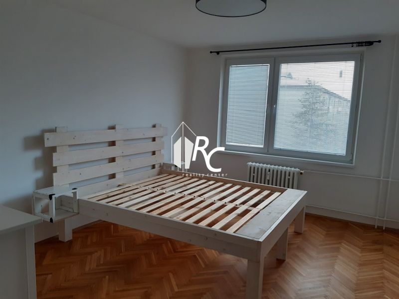 Helles Schlafzimmer mit Holzbett und Boden in Holzoptik in einer 2-Zimmer-Wohnung.