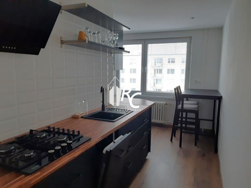 Küche in einer 2-Zimmer-Wohnung mit Holzboden und Bartisch.