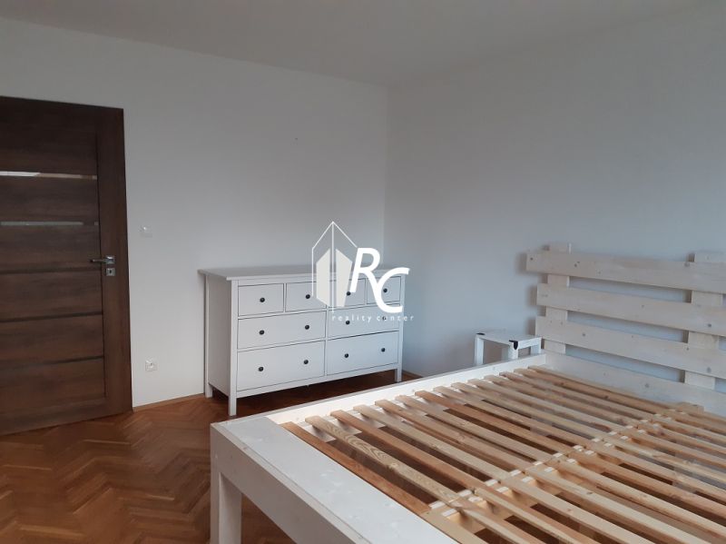 Schlafzimmer mit weißen Möbeln und Boden in Holzoptik in einer 2-Zimmer-Wohnung.