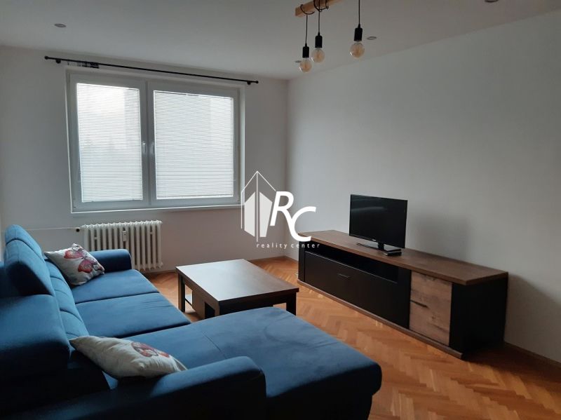 Wohnzimmer in einer Zweizimmerwohnung mit Ecksofa und Holzboden.