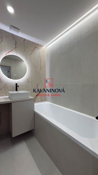 Badezimmer mit rechteckiger Badewanne und rundem Spiegel in einer 4-Zimmer-Wohnung.