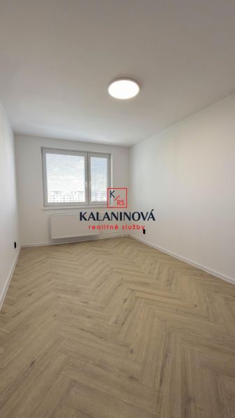 Ein Zimmer mit einem Holzboden-Dekor in einer 4-Zimmer-Wohnung, elegant erhellt durch ein großes Fenster.