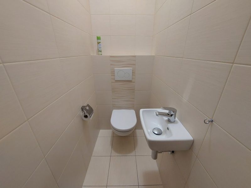 Toilette mit Waschbecken im Inneren einer 3-Zimmer-Wohnung, geflieste Wände.