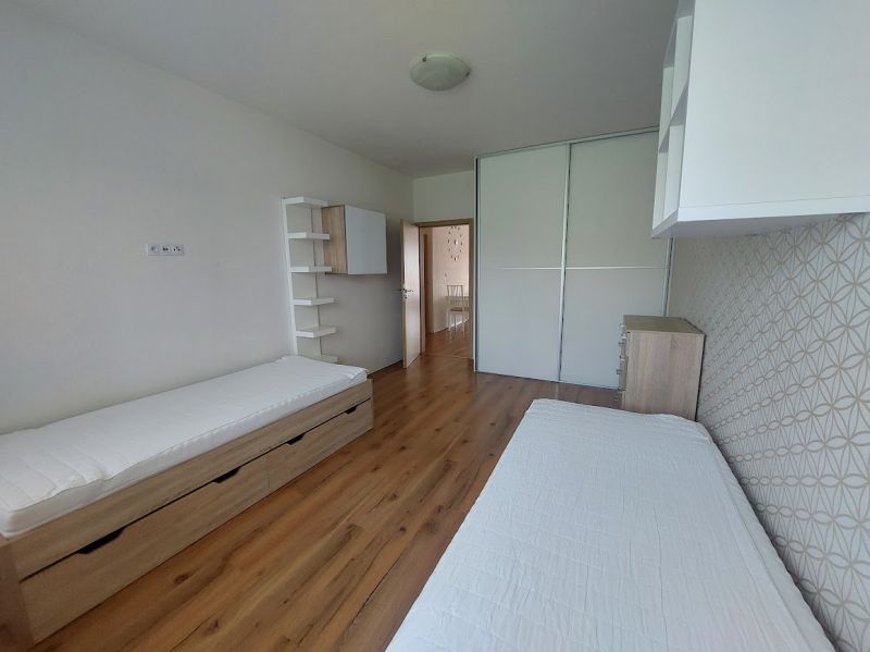 Ein Schlafzimmer in einer 3-Zimmer-Wohnung mit Holzboden, zwei Betten und einem Einbauschrank.