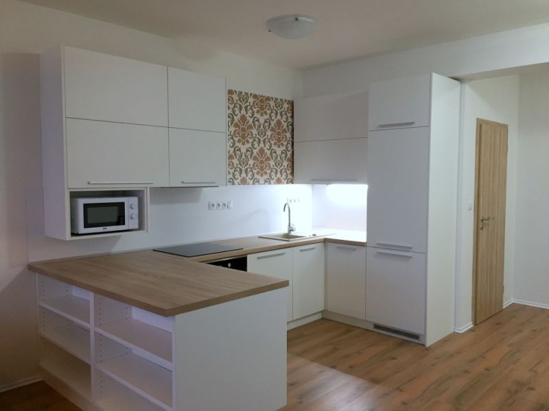 Eine Küche mit weißer Küchenzeile und dekorativer Wand in einer 3-Zimmer-Wohnung, Boden mit Holzdekor.