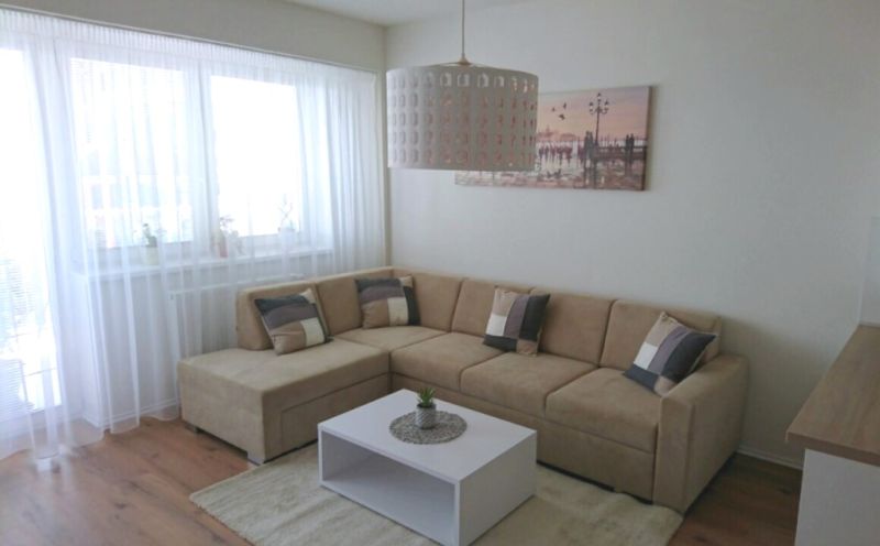 Wohnzimmer in einer 3-Zimmer-Wohnung mit Ecksofa und Holzboden.
