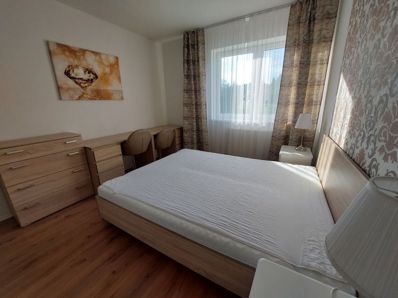 Schlafzimmer mit einem großen Bett, einem Boden mit Holzdekor und einem dekorativen Bild in einer 3-Zimmer-Wohnung.