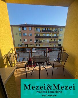 Der Balkon einer 2-Zimmer-Wohnung in Vlčkovce mit Tisch und Stühlen, Blick auf das Wohngebäude.