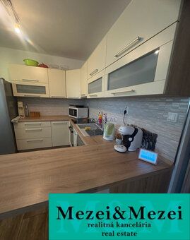 Küche in einer 2-Zimmer-Wohnung mit Holzboden und hellen Möbeln.