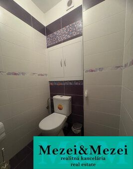 Badezimmer in einer 2-Zimmer-Wohnung mit Fliesen in Weiß- und Violetttönen.